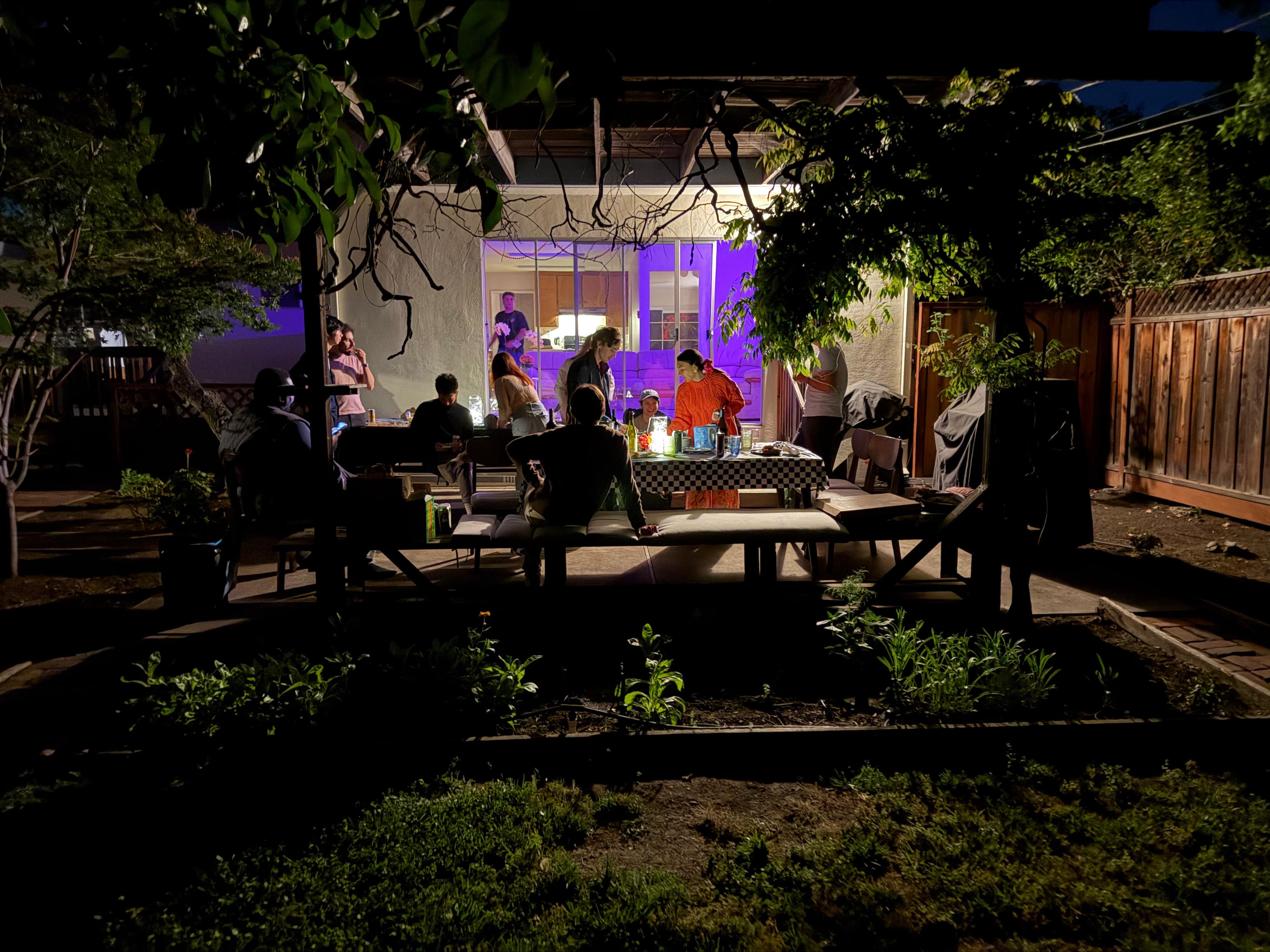 Garage HQ backyard at night with founders working under purple light